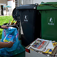 Man recycleert papier, glas, plastiek en ander afval in verschillende vuilniscontainers, België
